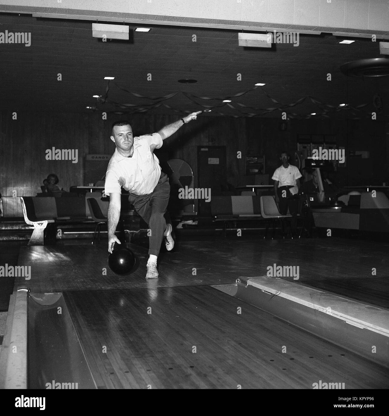 Années 1960, historique, un bowling, un homme tenant une balle bolwling sur le point de laisser tomber au fond d'une voie dix broches bolwling alley, USA. Banque D'Images