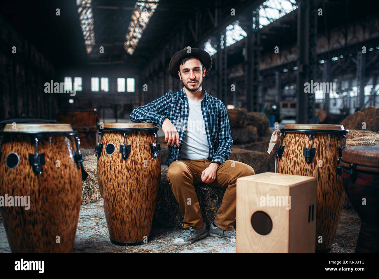 Jeune homme africain batteur posent contre tambour en bois, magasin d'usine sur l'arrière-plan. Le djembé, instrument de percussion musicale, bongo beats Banque D'Images