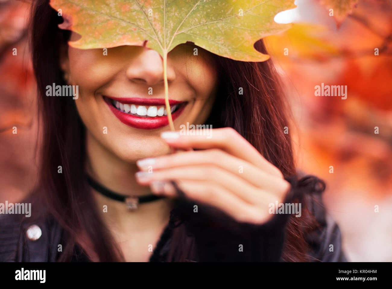 Portrait d'une femme brune avec une feuille et des dents blanches en saison d'automne. Banque D'Images