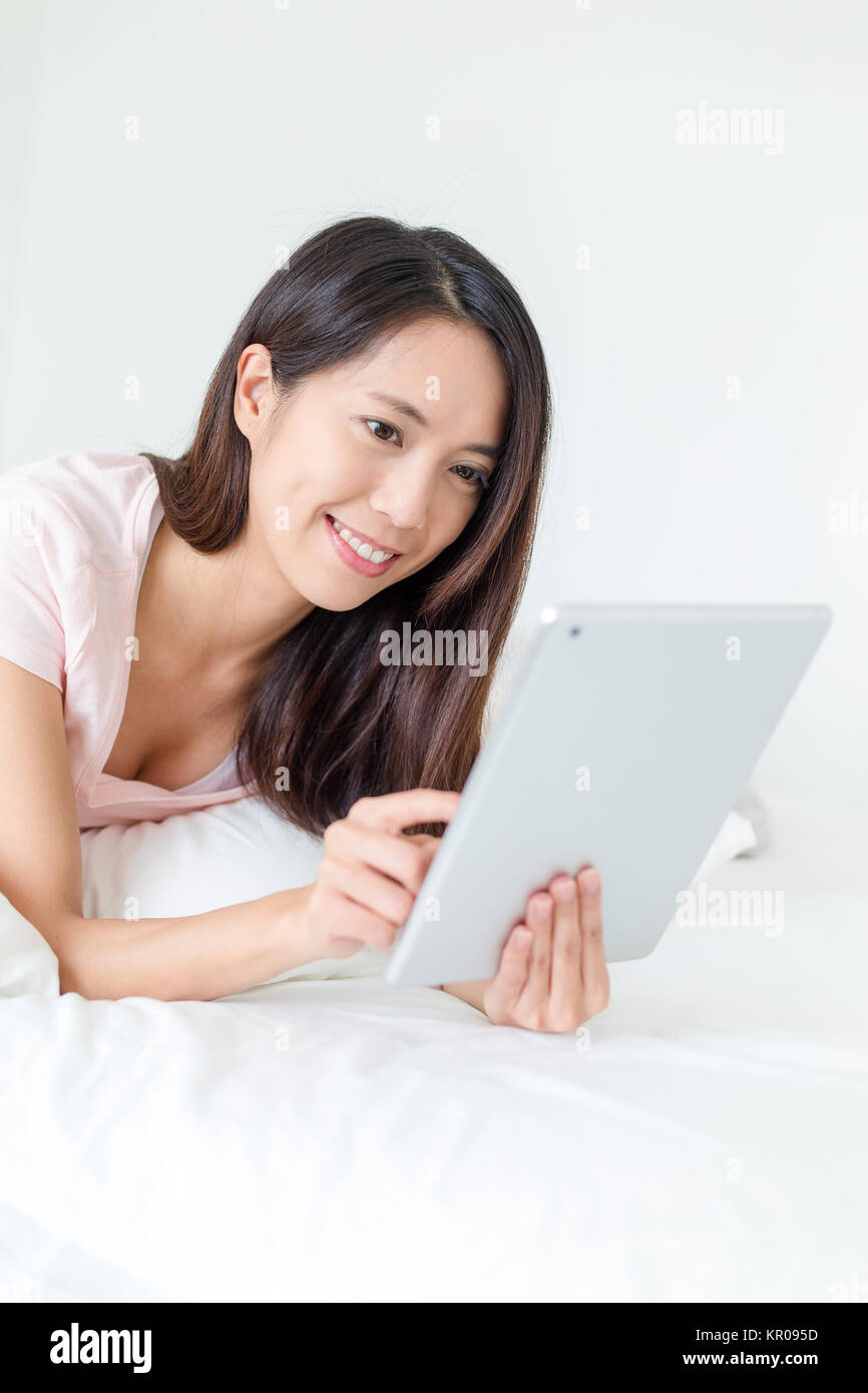 Woman working on tablet computer on bed Banque D'Images