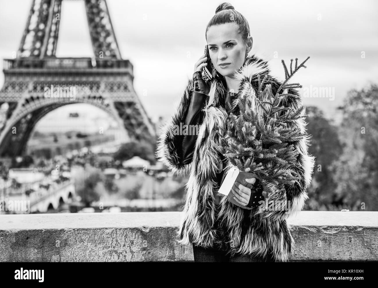 La saison des festivals à Paris. la mode moderne-monger avec arbre de Noël en manteau de fourrure contre la tour Eiffel à Paris, France talking on a cell phone Banque D'Images