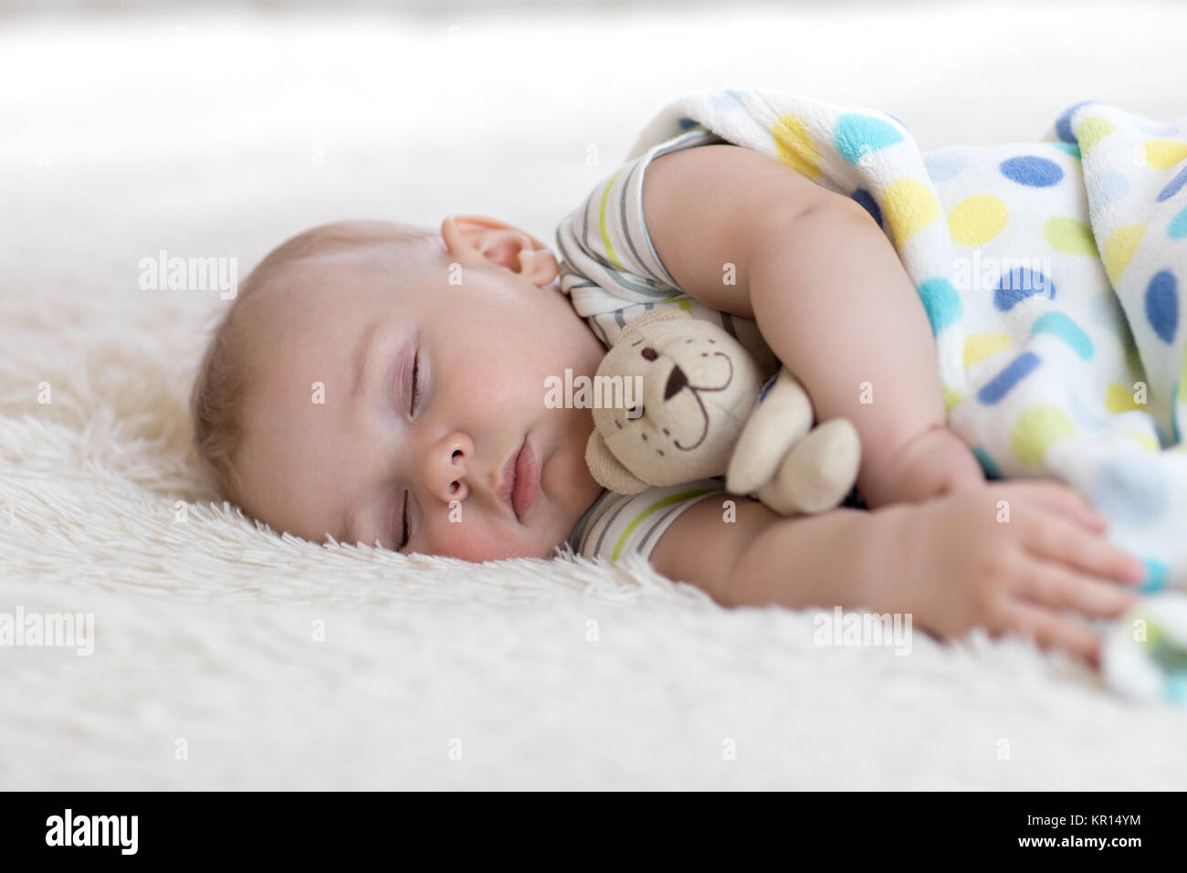 Bébé endormi dans son lit, holding a teddy bear Banque D'Images