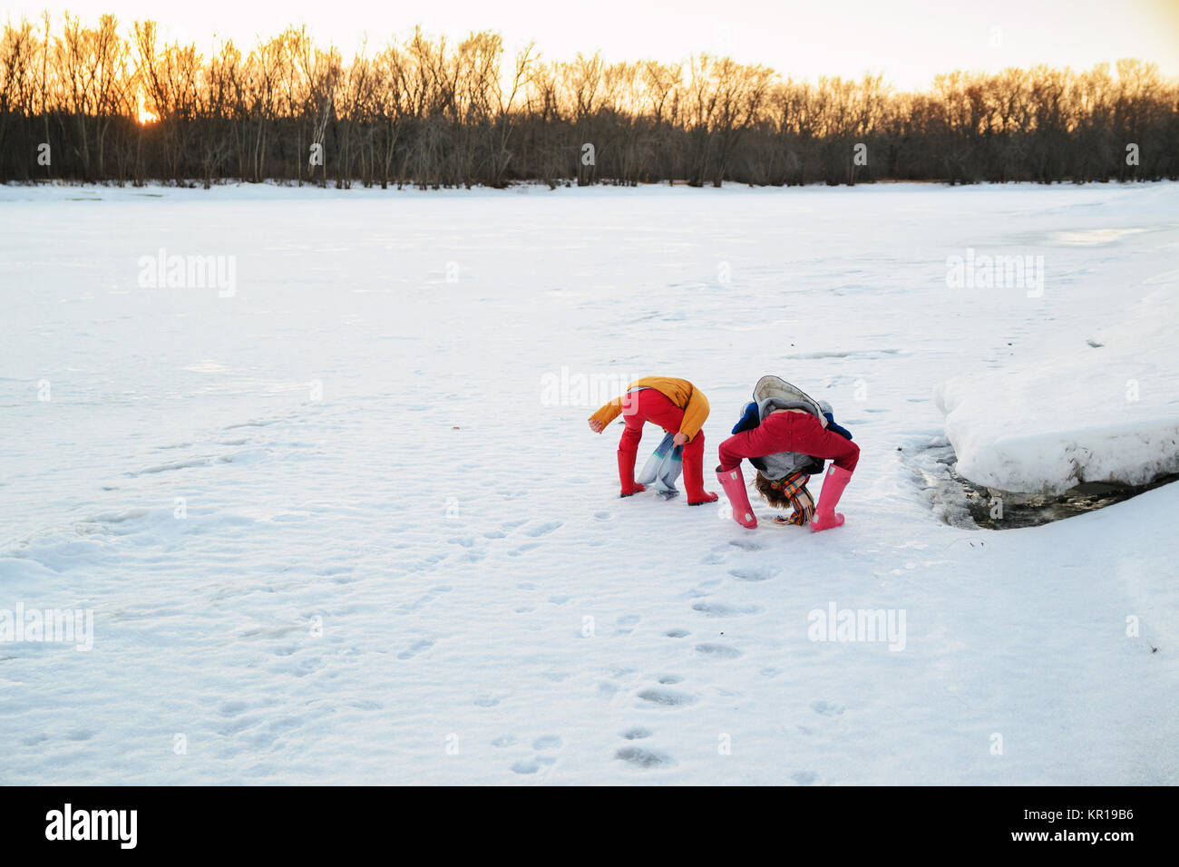 Vue arrière de deux garçons debout sur un lac gelé à la recherche entre les jambes Banque D'Images
