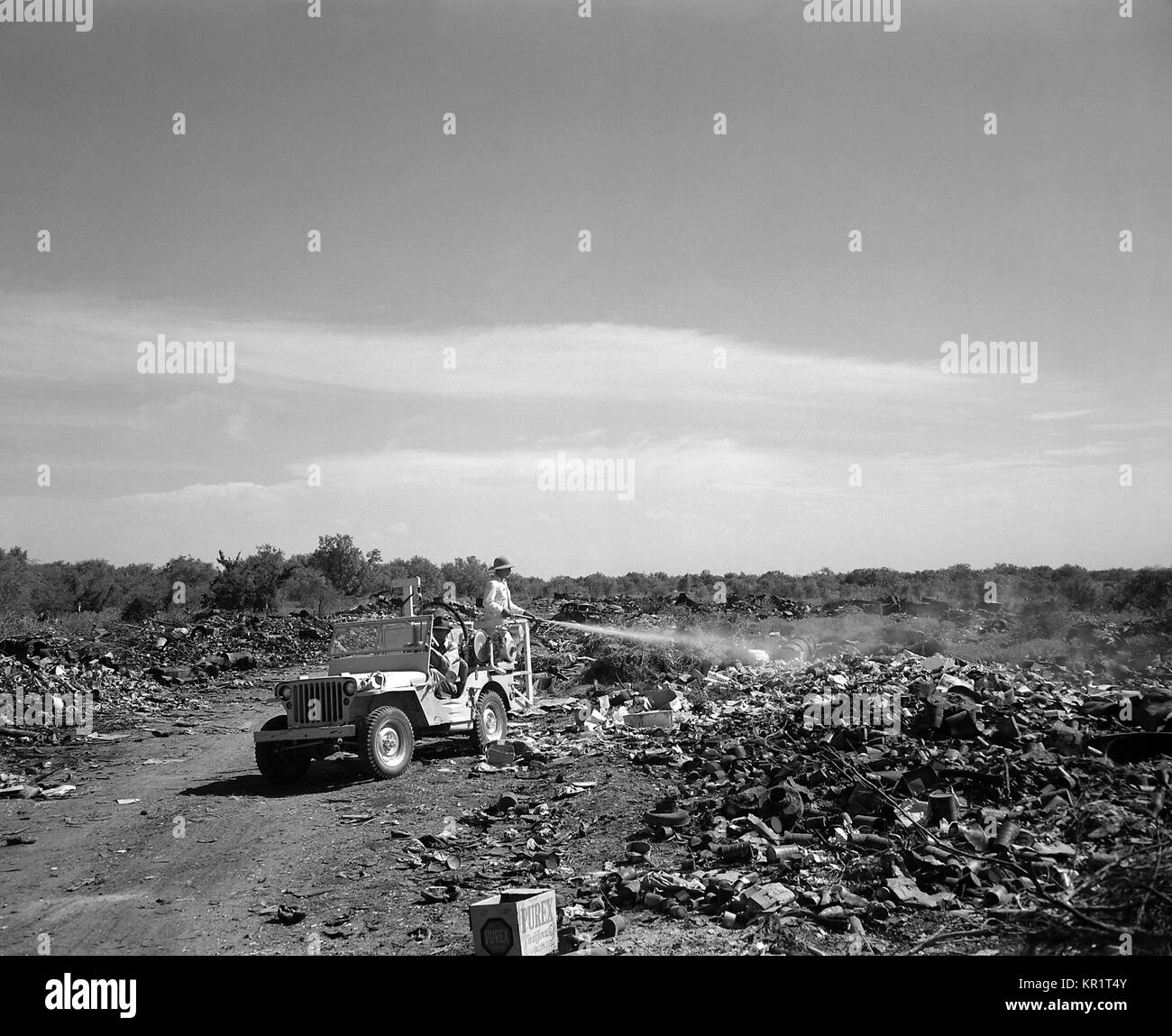 Homme debout à l'arrière d'une jeep une pulvérisation de mouche en décharge de la ville de Edinburg, Texas, 1946. Les mouches peuvent transmettre des maladies d'origine alimentaire telles que le choléra, la typhoïde, la paratyphoïde, la salmonellose et la dysenterie, ainsi que myiase, le trachome, et le pian. Ils se reproduisent dans les déchets organiques, les déchets et les excréments. Image courtoisie CDC. Banque D'Images