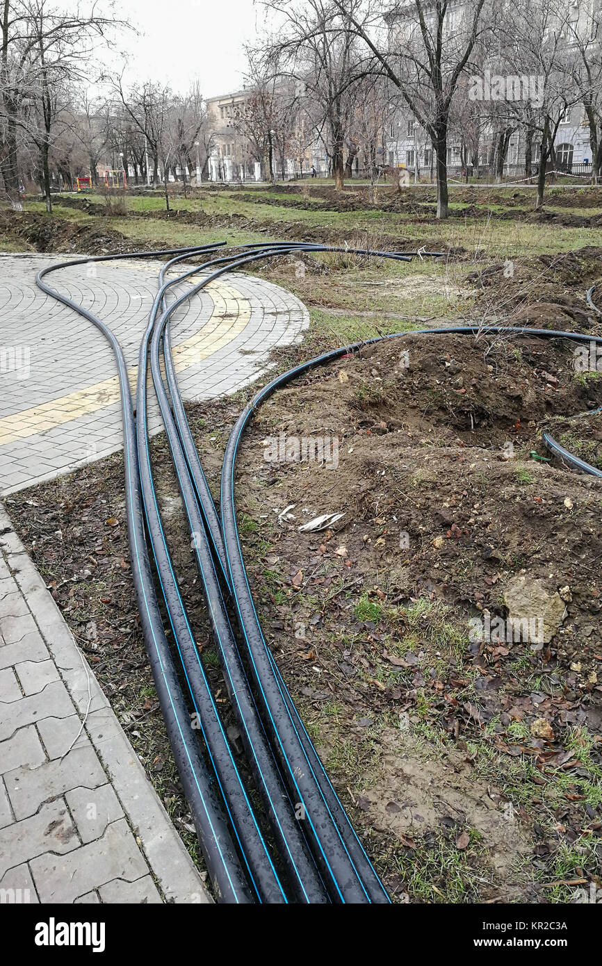 Pose de la protection de l'oléoduc dans le sol des tranchées pour le système d'irrigation souterrain, le système d'irrigation, les travaux municipaux à la fin de l'automne dans le parc Banque D'Images