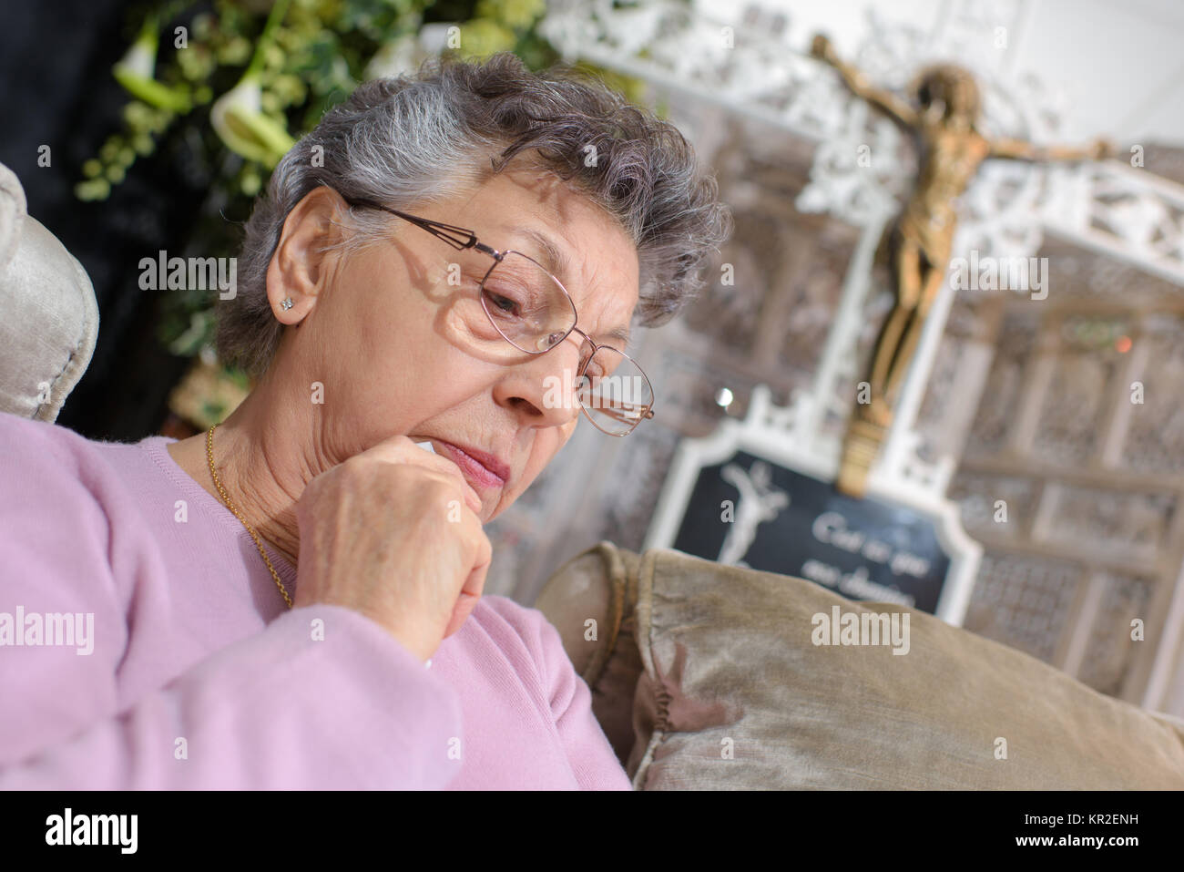 Femme âgée en face de crucifix Banque D'Images