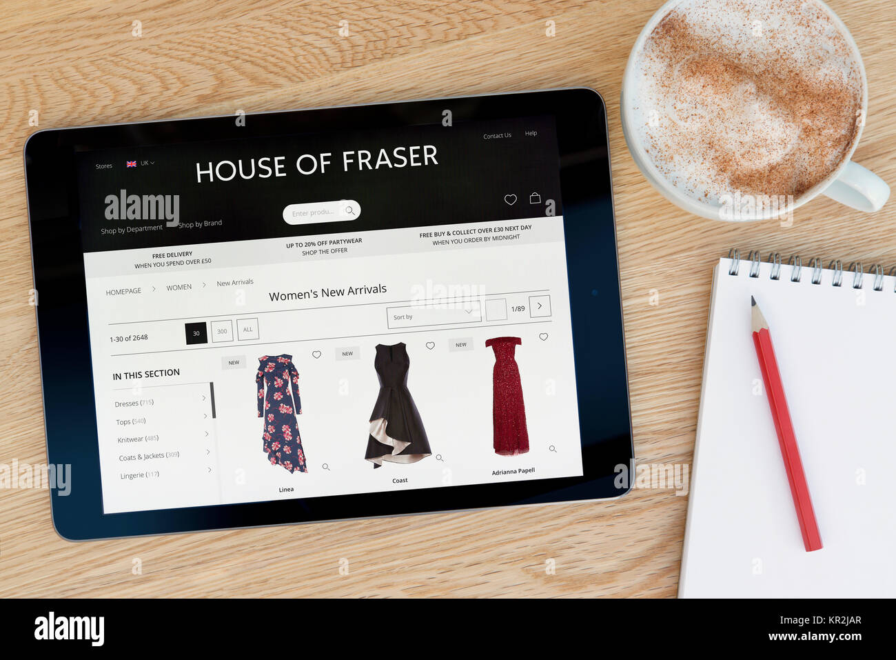 La House of Fraser Site sur un iPad tablet device qui repose sur une table en bois à côté d'un bloc-notes et un crayon et une tasse de café (rédaction uniquement) Banque D'Images
