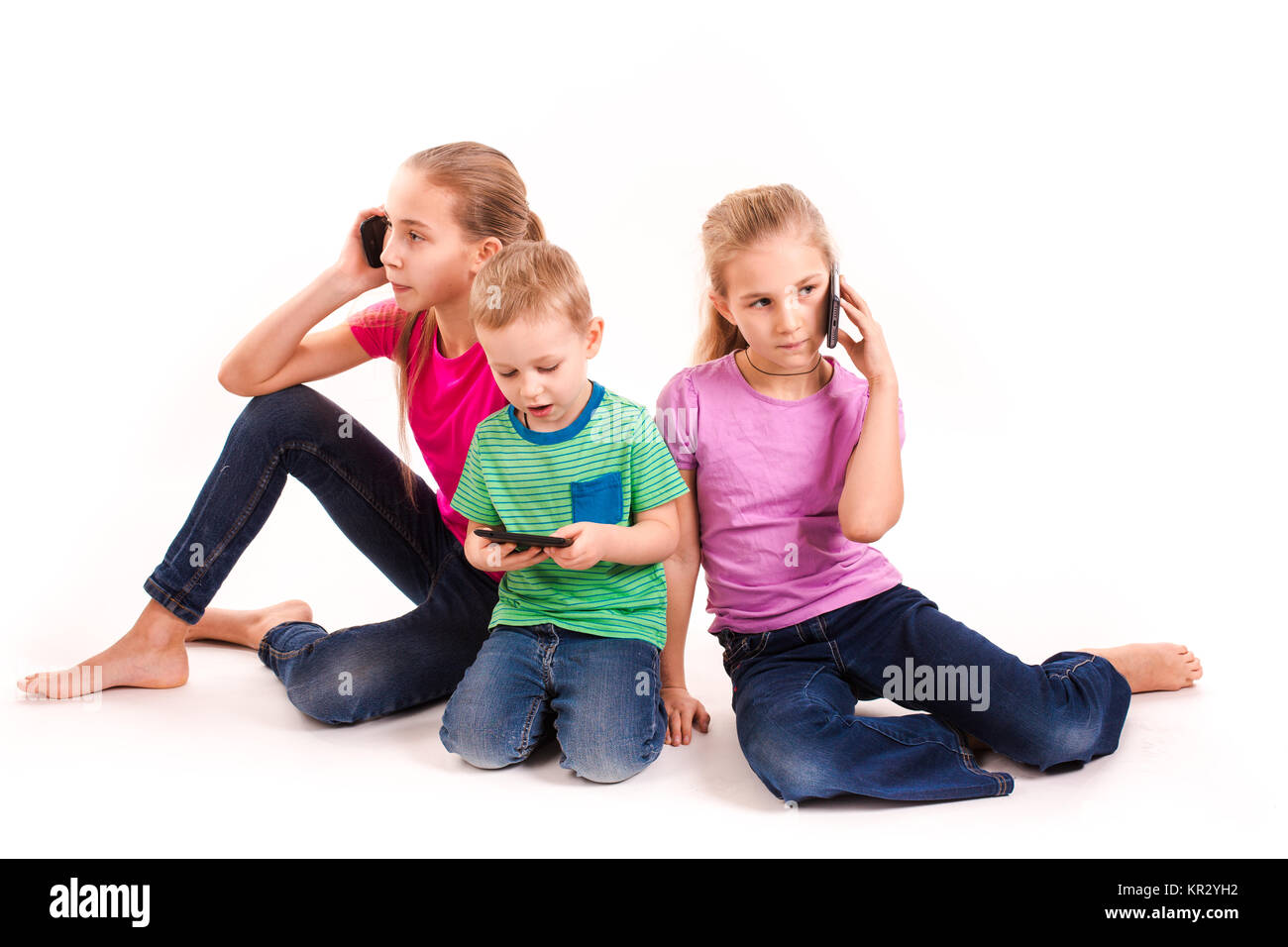 Groupe des petits enfants à l'aide de dispositifs électroniques isolé sur blanc. Banque D'Images