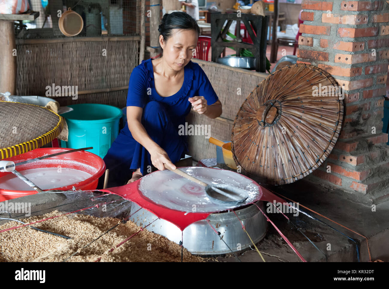 Une femme dans Ben Tre montre comment rendre les papiers de riz pour rouleaux de printemps vietnamiens. Banque D'Images