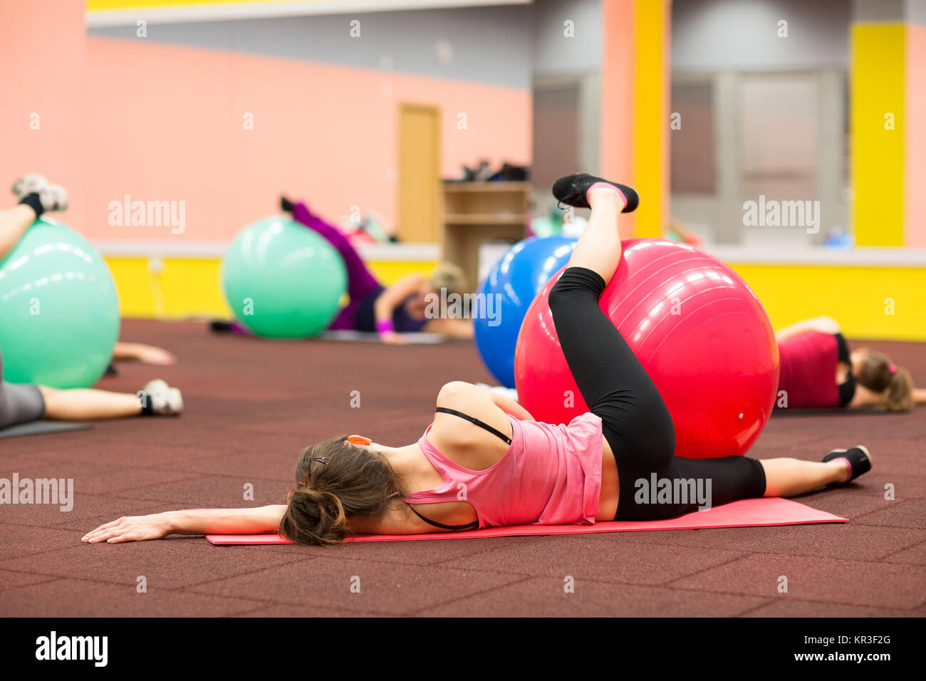 Les personnes du groupe dans un cours de gym pilates - jeune femme avec formation de remise en forme de balle (shallow DOF, tons de couleur libre) Banque D'Images