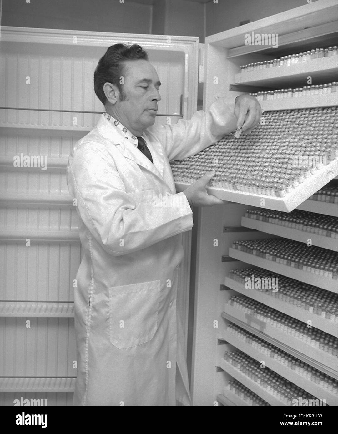 Technicien de laboratoire Chuck Peters examine les étiquettes sur les fioles de sérum, 1977. Flacons de sérum contiennent des informations sur la nutrition, la santé, des maladies et des styles de vie, 1977. Image courtoisie CDC/K. Seigneur. Banque D'Images