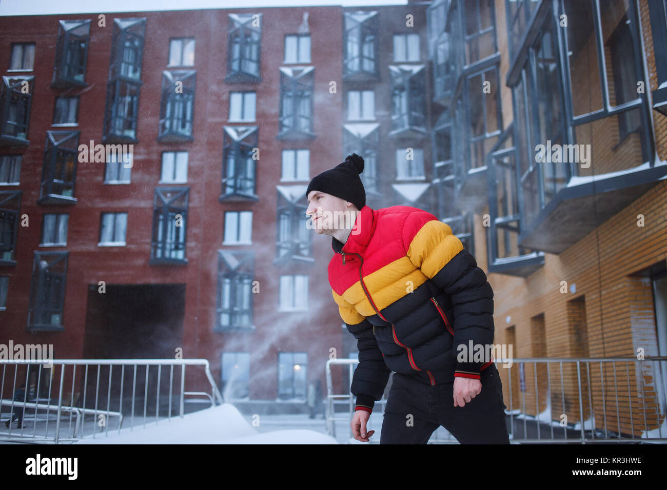 Homme fort avec des vêtements d'hiver dans la neige, bénéficie d'froid, neige, blizzard. Fond de cour urbaine Banque D'Images