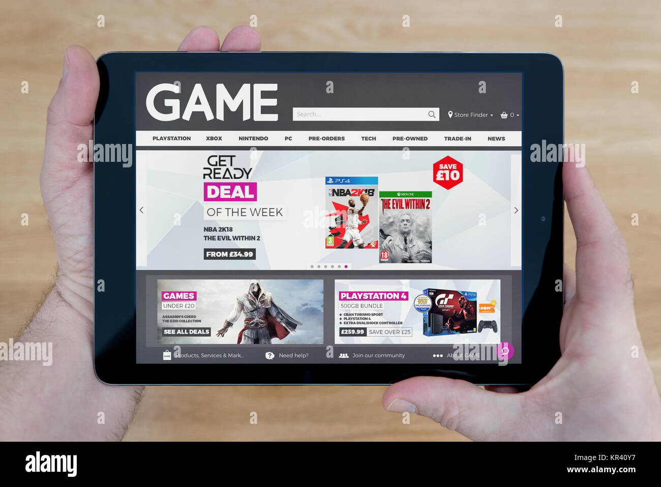 Un homme se penche sur le site web du jeu sur son iPad tablet device, tourné contre une table en bois page contexte (usage éditorial uniquement) Banque D'Images