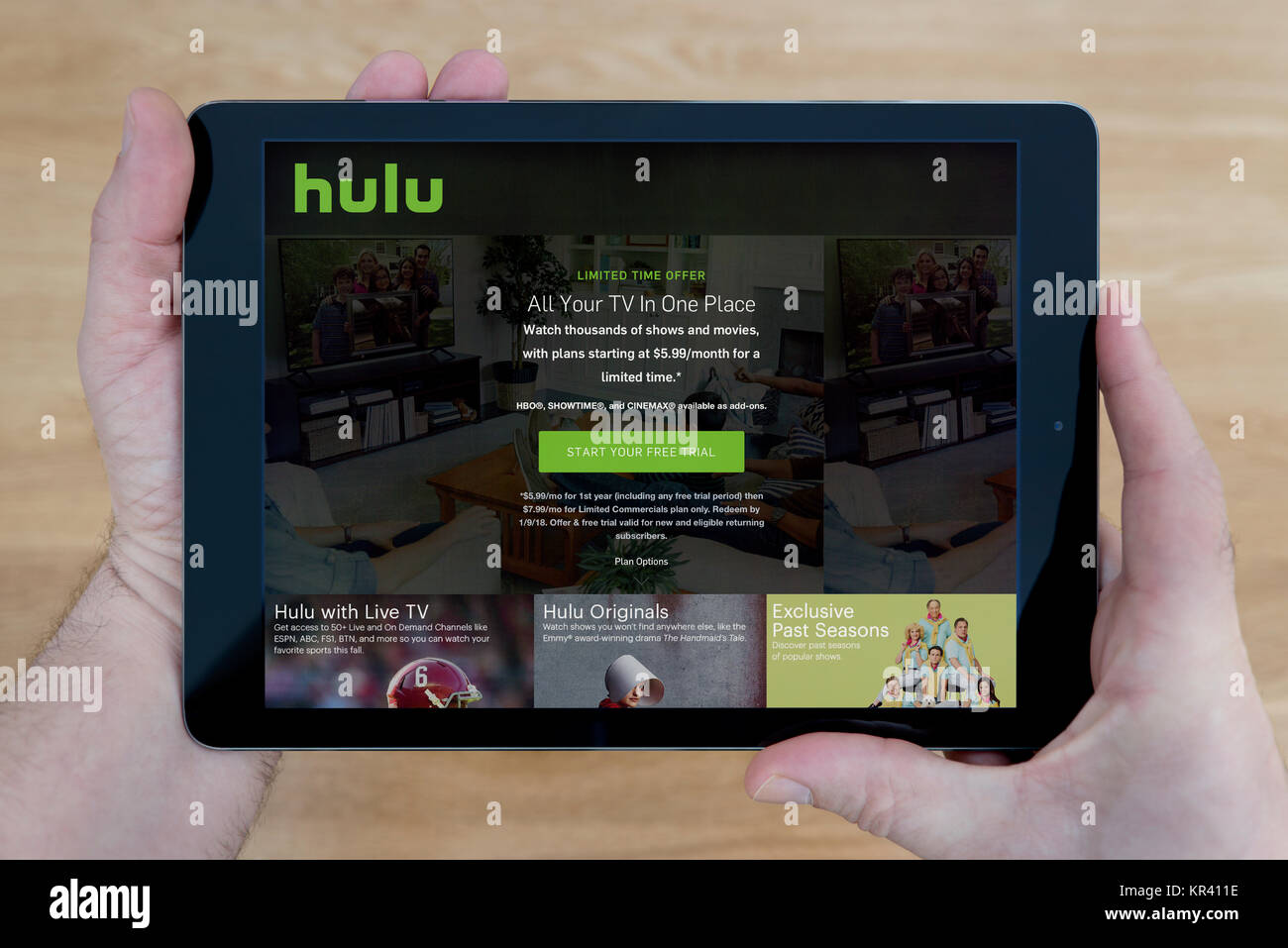 Un homme regarde le site web Hulu sur son iPad tablet device, tourné contre une table en bois page contexte (usage éditorial uniquement) Banque D'Images