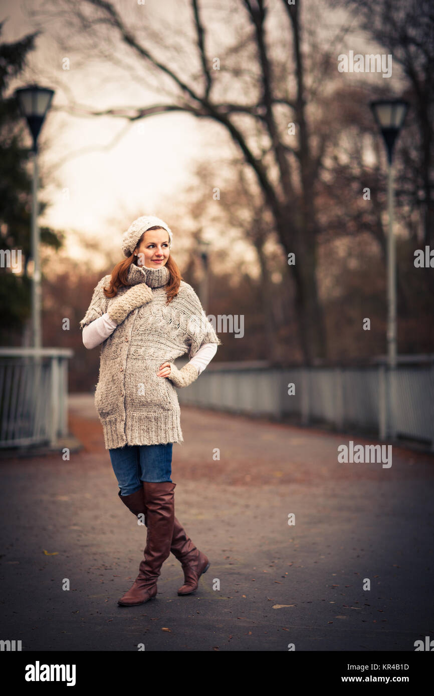 Automne/Hiver : portrait jeune femme vêtue d'un cardigan en laine chaude posant dehors dans un parc de la ville Banque D'Images