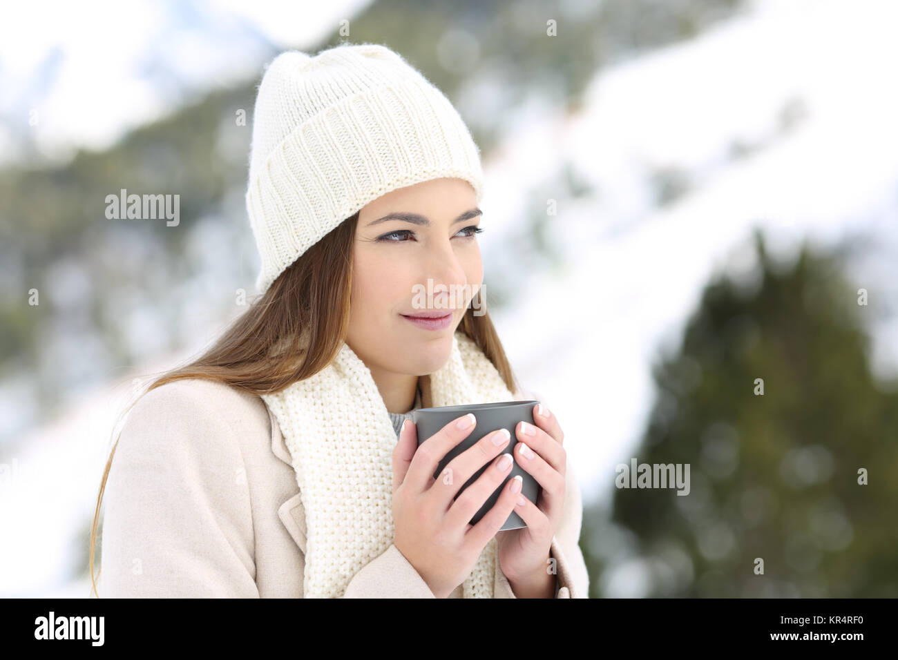 Pensive woman holding une tasse à café en vacances d'hiver dans la montagne enneigée Banque D'Images