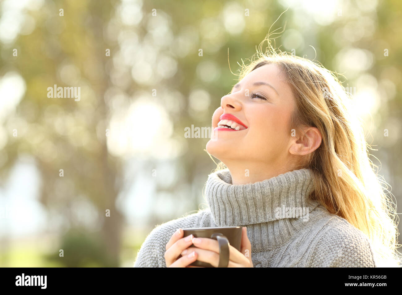 Portrait of a happy dame portant un maillot gris de respirer l'air frais tenant une tasse de café dans un parc en hiver Banque D'Images