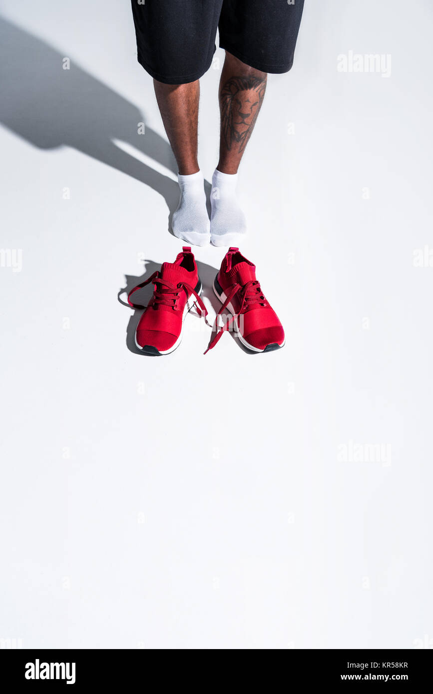 Portrait de sportif dans des chaussettes et chaussures de sport rouge sur gris Banque D'Images