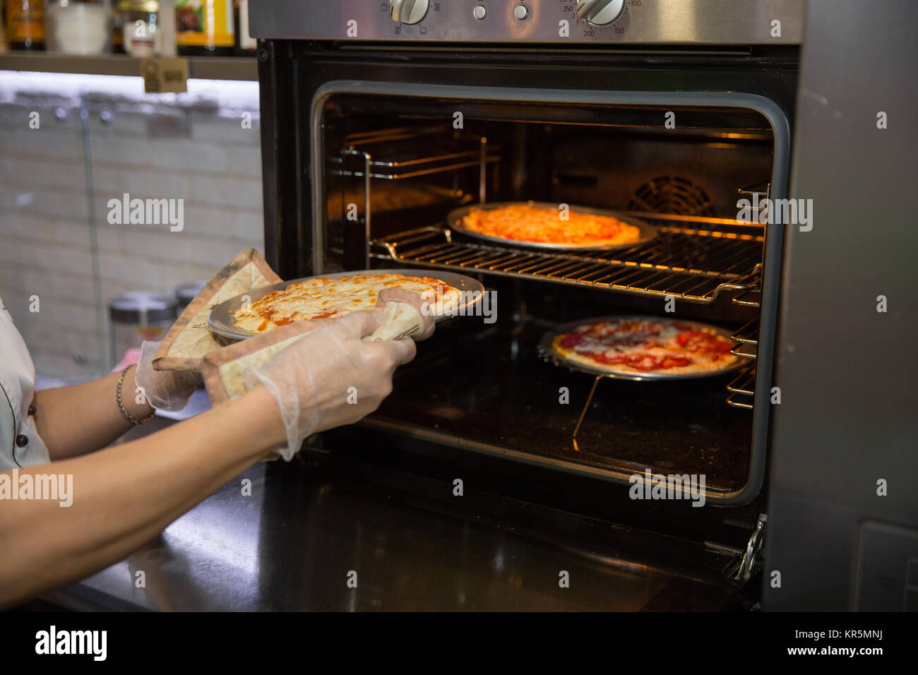 Cropped shot des mains du cuisinier dans la région de gant de cuisine en tenant la pizza de four. test de disponibilité Banque D'Images
