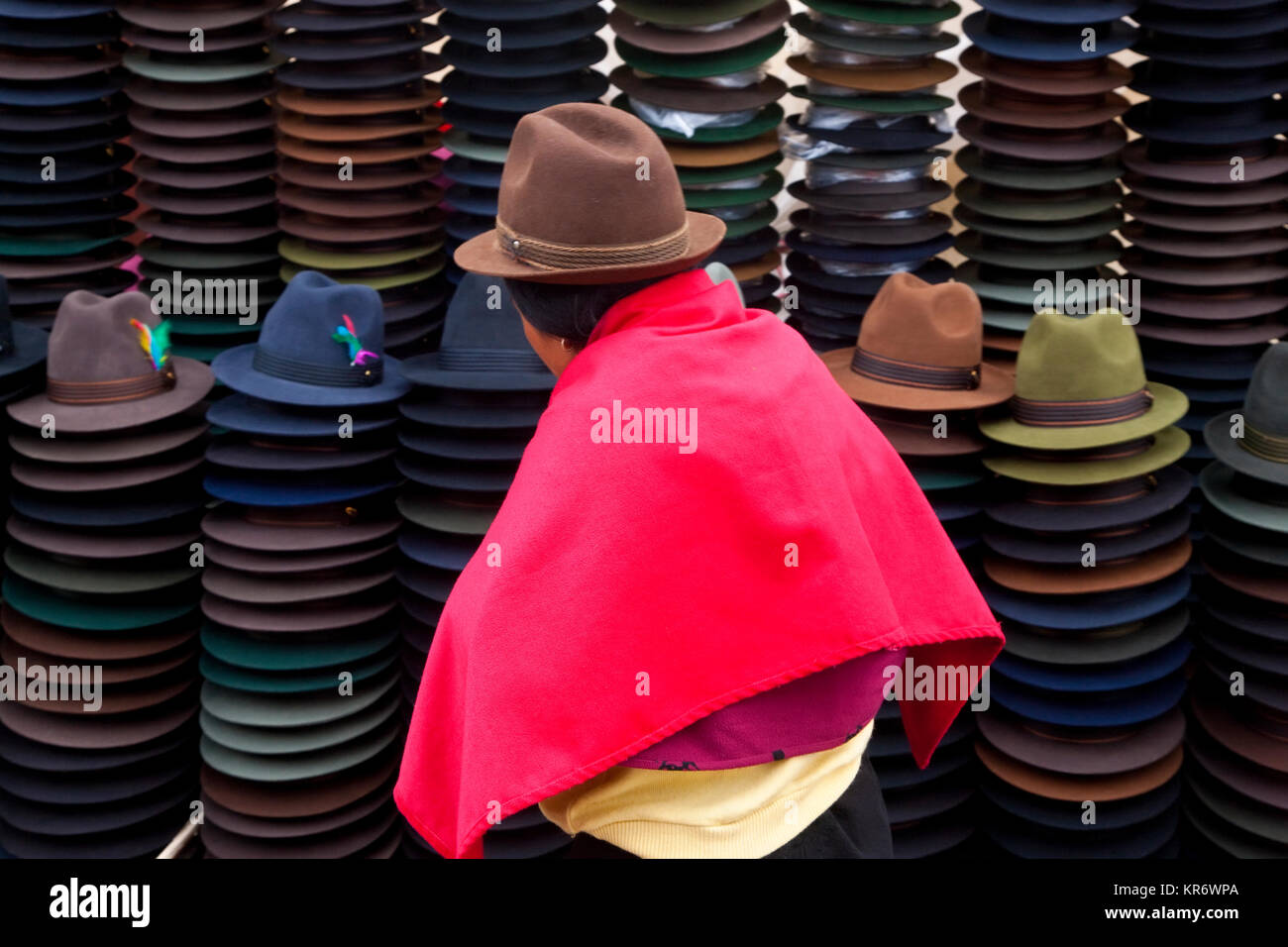 Vue arrière de femme portant chapeau brun et rose lumineux poncho vente de chapeaux de feutre traditionnel équatorien. Banque D'Images