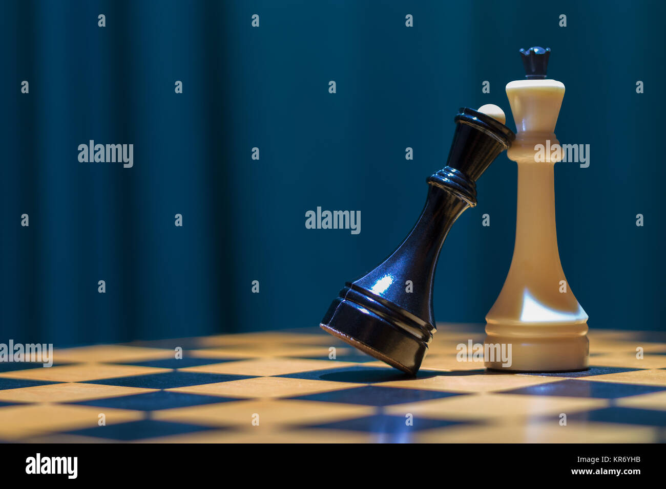 Noir et blanc d'échecs reine roi debout sur un échiquier en bois. La reine noire mit sa tête sur la poitrine pour le roi blanc. Banque D'Images