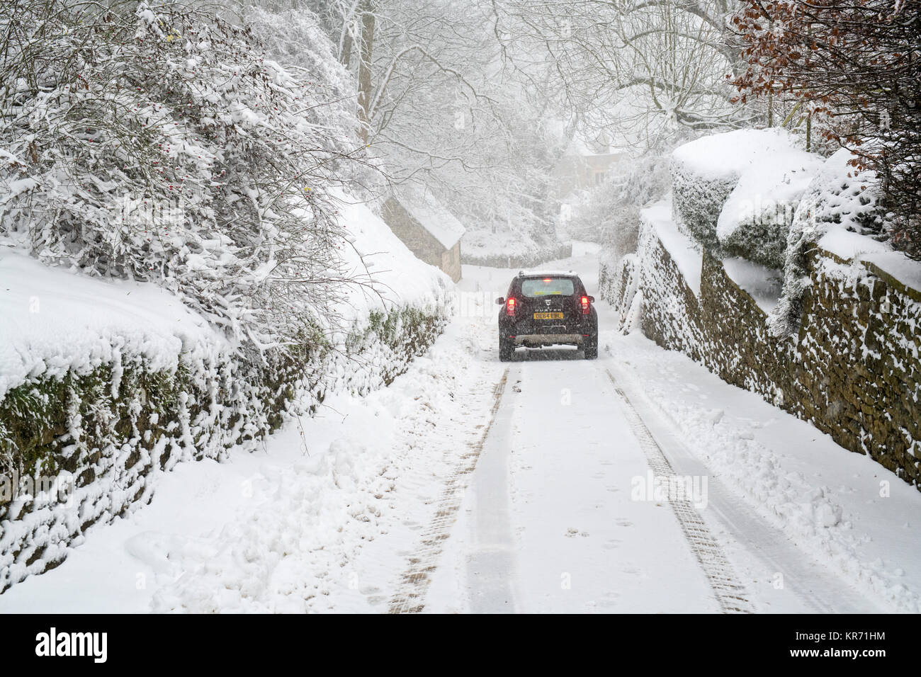 Dacia Duster en voiture sur une route de campagne enneigée près de Snowshill village en décembre. Snowshill, Cotswolds, Gloucestershire, Angleterre Banque D'Images