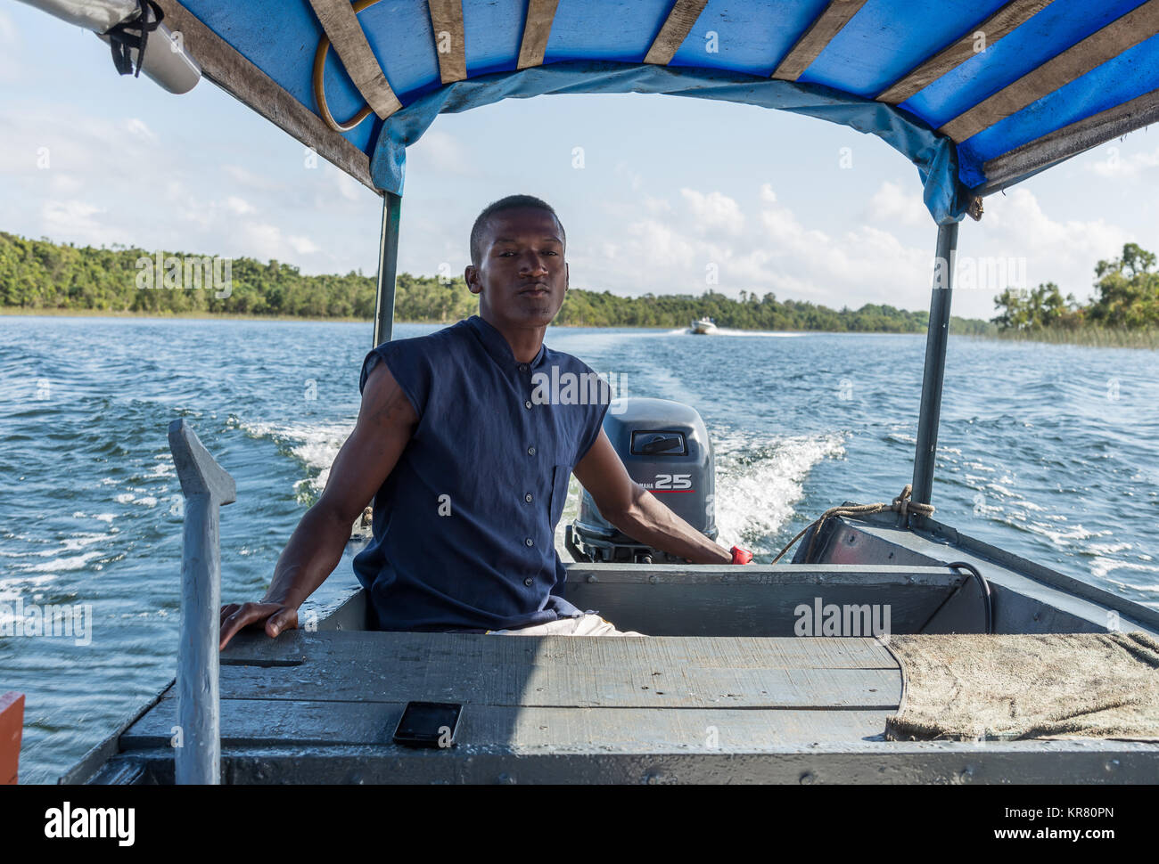 Un homme malgache conduit un bateau à moteur dans le lac Ampitabe. Madagascar, l'Afrique. Banque D'Images