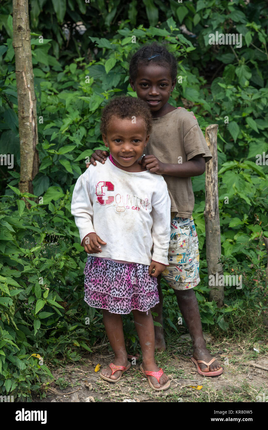 Deux belles jeunes filles malgaches debout près de buissons verts. Madagascar, l'Afrique. Banque D'Images