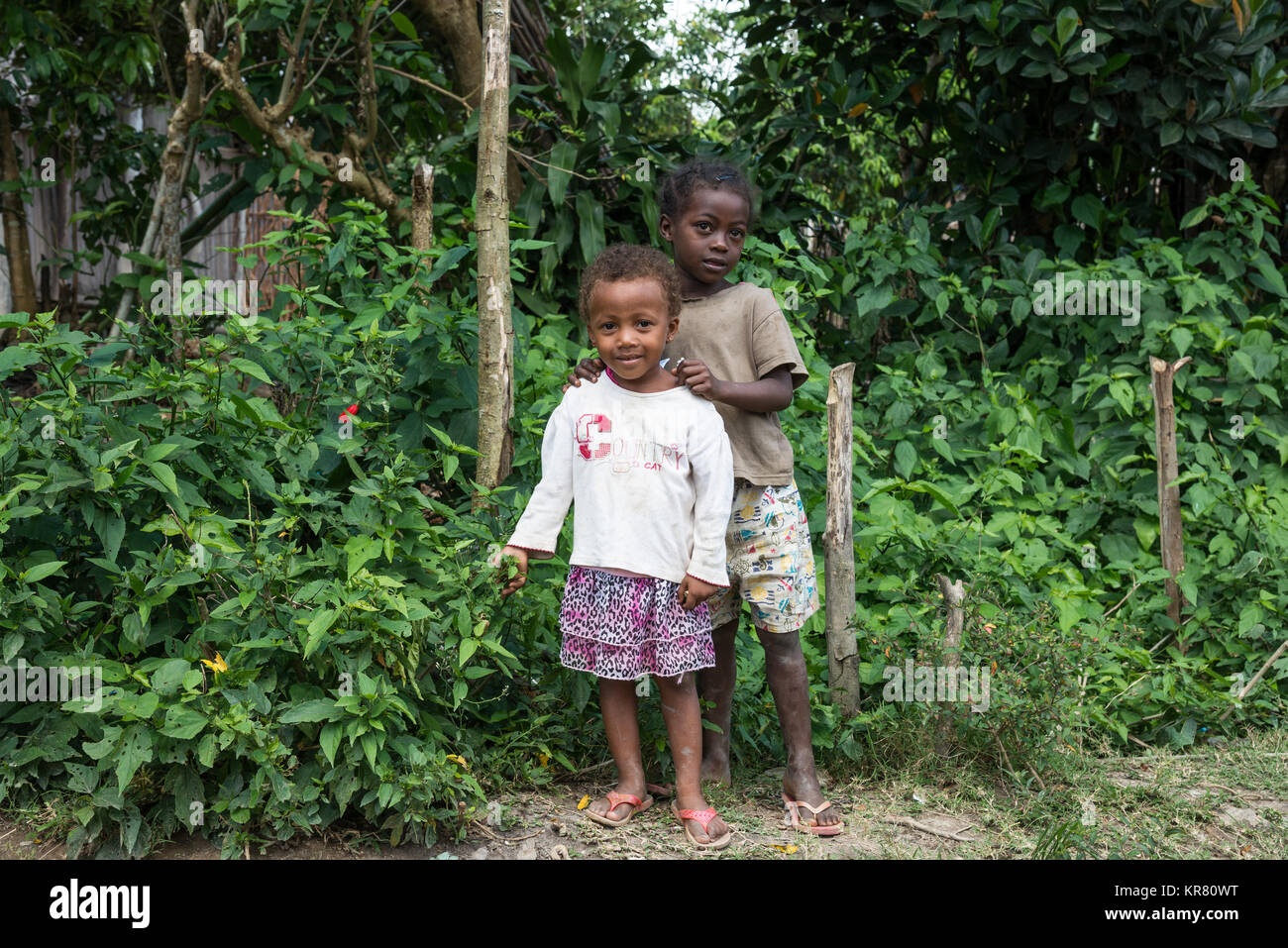 Deux belles jeunes filles malgaches debout près de buissons verts. Madagascar, l'Afrique. Banque D'Images