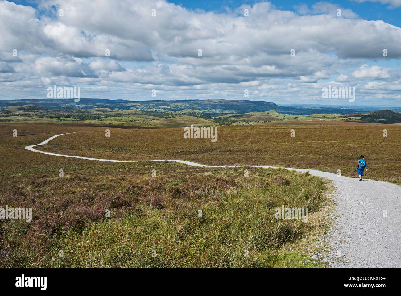 L'Irlande, le comté de Cavan, Cuilcagh Mountain Park, Woman walking along winding road Banque D'Images