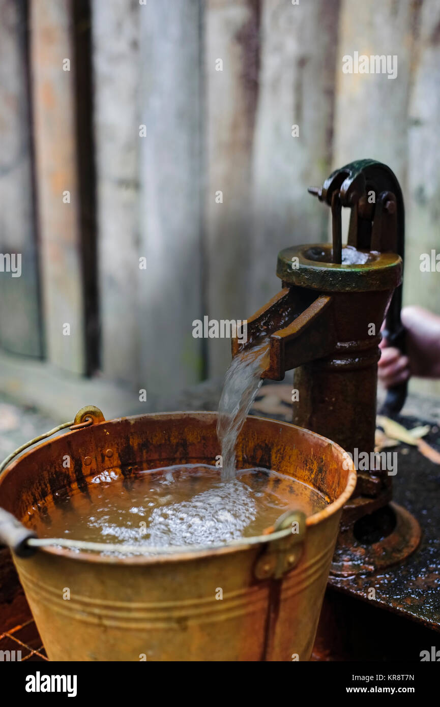L'eau du seau de verser dans la pompe à eau Banque D'Images