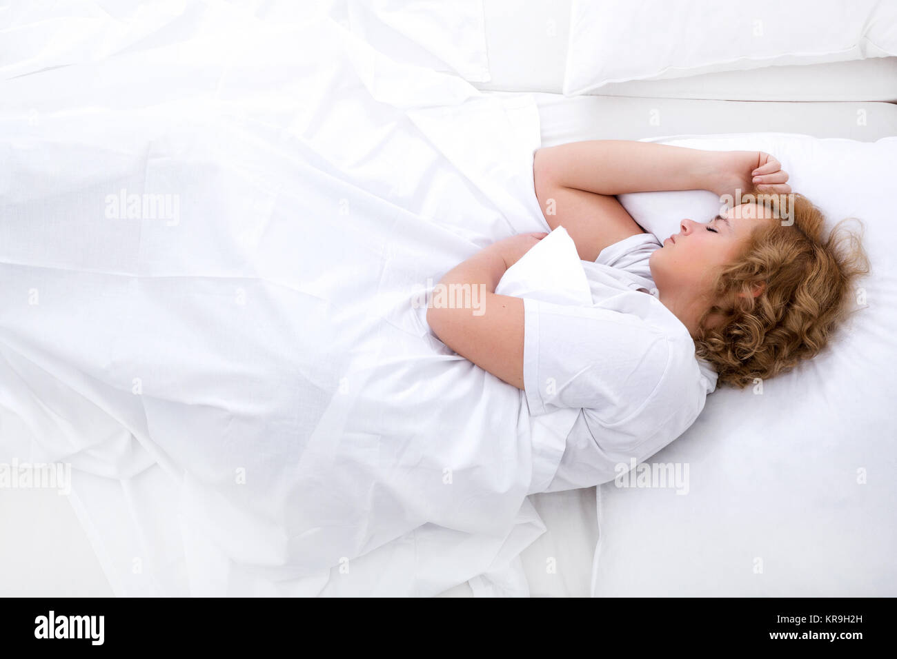 Une jeune femme taille plus dormir dans le lit. Banque D'Images
