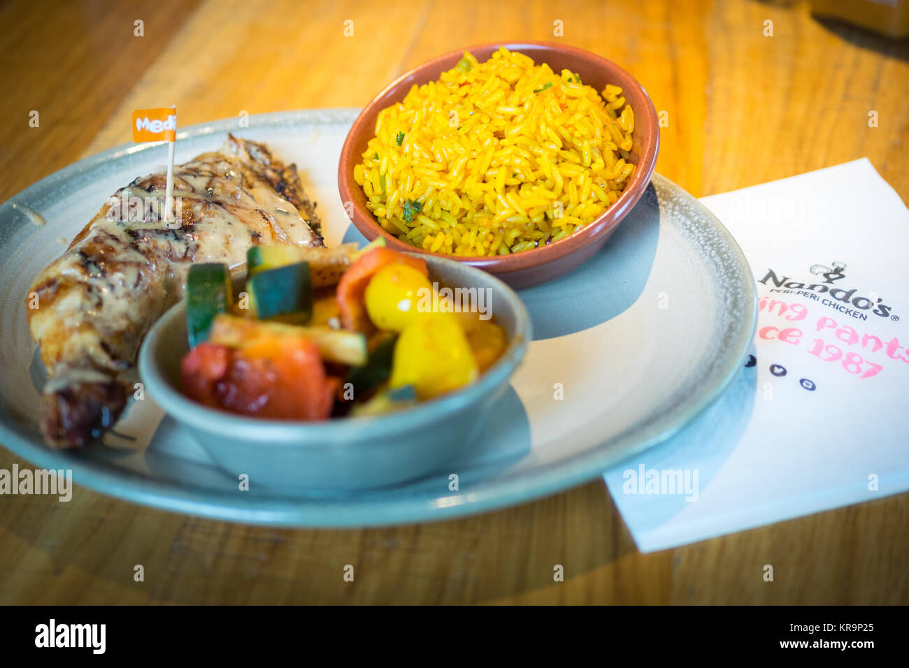 Peri-peri Quart de poulet avec riz épicé de côtés et peri-peri légumes de Nando's, une chaîne de restauration décontractée qui provient d'Afrique du Sud. Banque D'Images