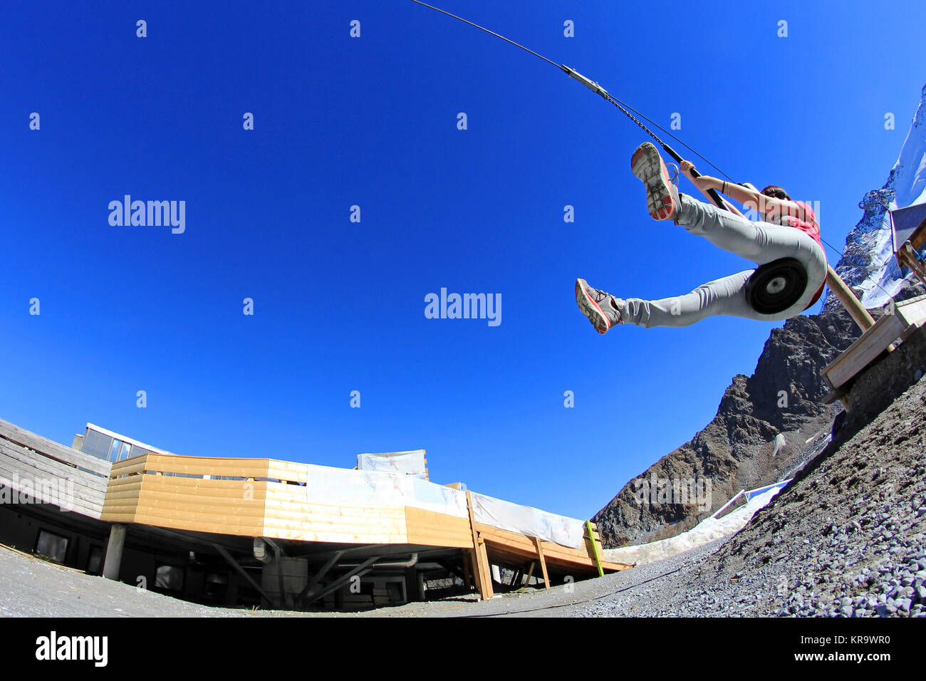Une jeune femme glisse sur une corde de rappel dans les montagnes Banque D'Images