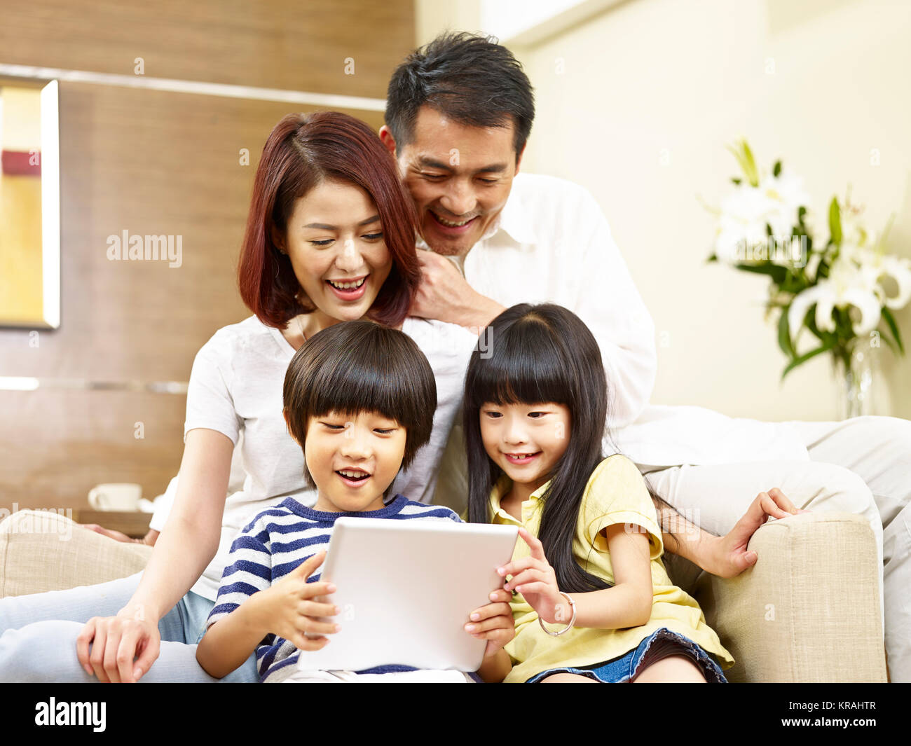 Les parents asiatiques mère et père et fils et fille de deux enfants assis sur la table à l'aide de la tablette numérique ensemble. Banque D'Images