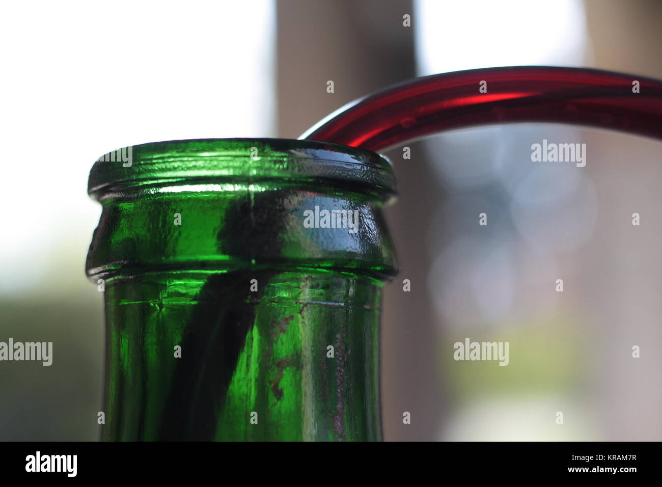 Bouteille verte top close up detail avec de la paille tout en remplissant avec du vin rouge. Banque D'Images