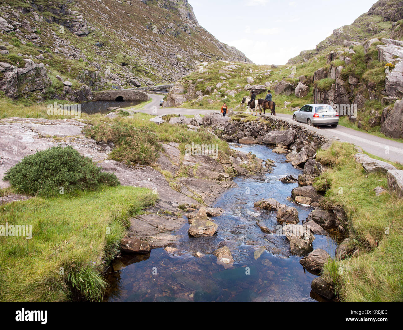 La rivière Loe et étroite route de montagne à travers la vallée du vent raide de Gap of Dunloe, niché dans la Macgillycuddy Reeks montagnes d'Irel Banque D'Images
