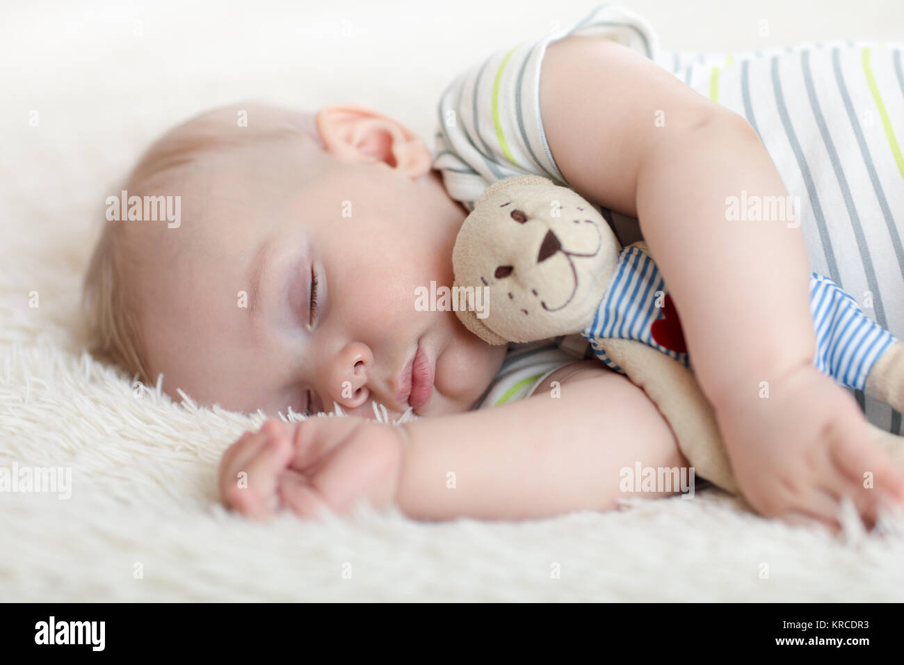 Mignon bébé garçon endormi avec petit jouet Banque D'Images