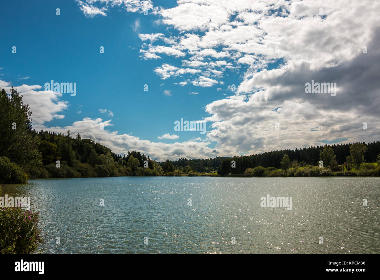 Lac solitaire avec reflets dans l'eau et les forêts autour de et ciel bleu avec des nuages Banque D'Images