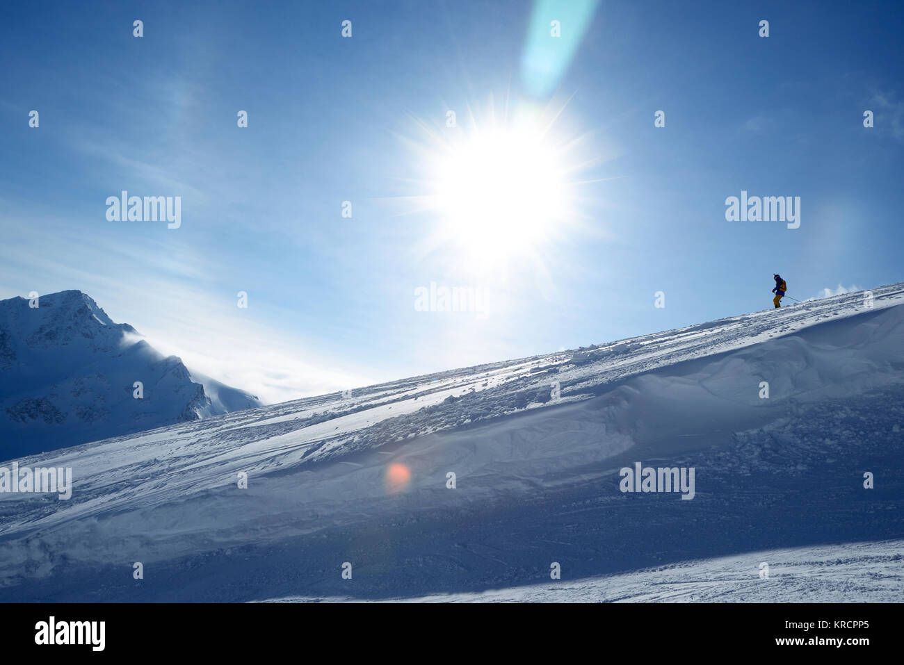 La descente des skieurs de pente sur un fond de ciel bleu et les montagnes Banque D'Images