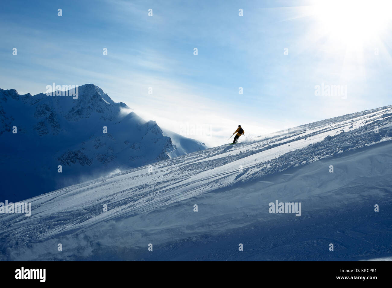 La descente des skieurs de pente sur un fond de ciel bleu et les montagnes Banque D'Images