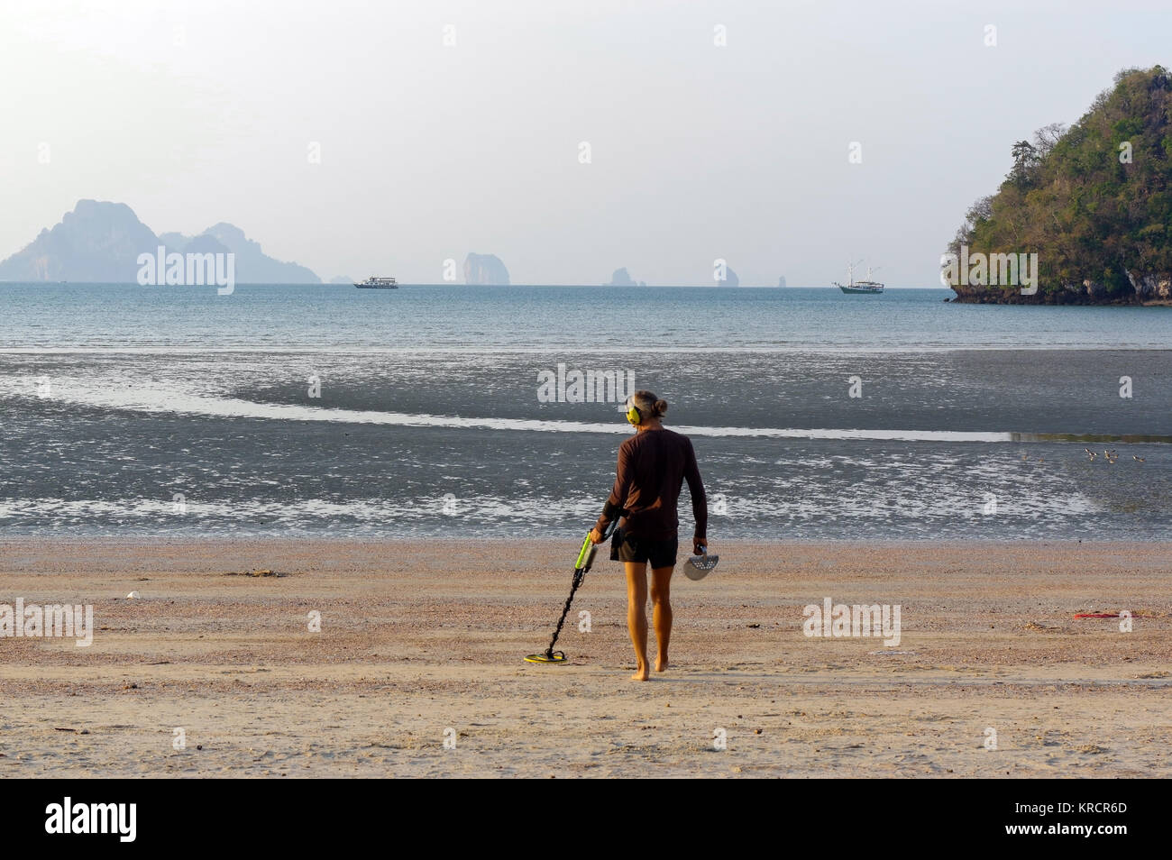 Chasseur de trésor avec détecteur de métal sur le sunrise beach Banque D'Images