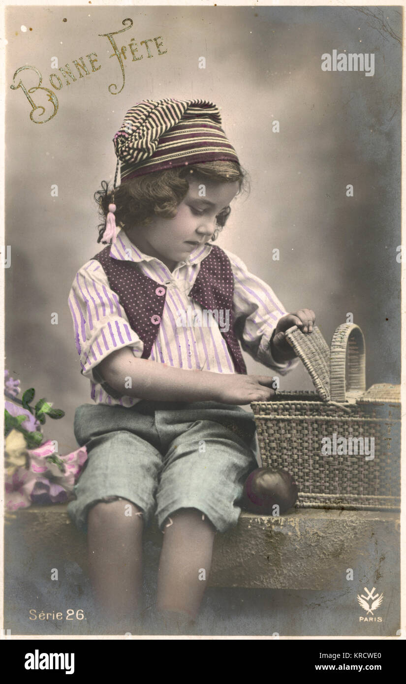 Un petit garçon regarde à l'intérieur son panier de pique-nique. Date : vers 1900 Banque D'Images