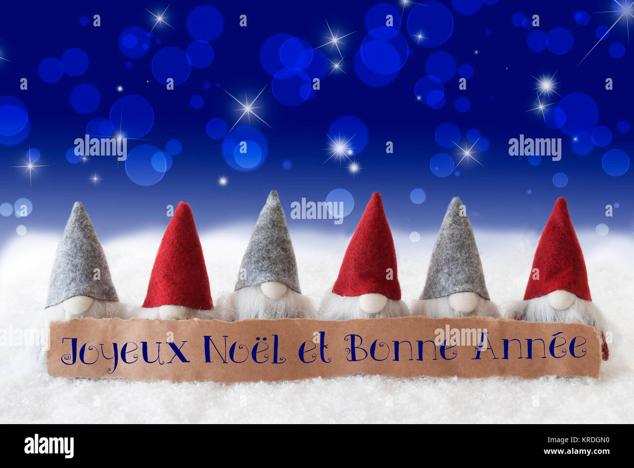 Étiquette avec texte français Joyeux Noel et Bonne Annee signifie joyeux  Noël et Bonne Année. Carte de Vœux de Noël avec les gnomes. Bokeh mousseux  et fond bleu avec de la neige