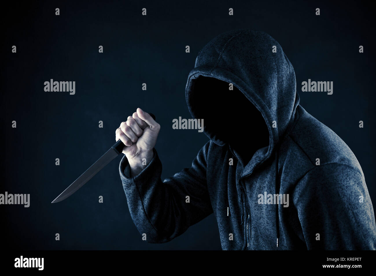 Homme cagoulé avec un couteau dans le noir Banque D'Images