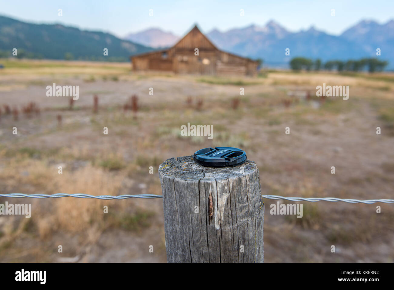 Bouchon d'objectif mis sur poteau de clôture en bois en face de T.A.Moulton Grange, Grand Tetons National Park, Wyoming, comté de Teton Banque D'Images