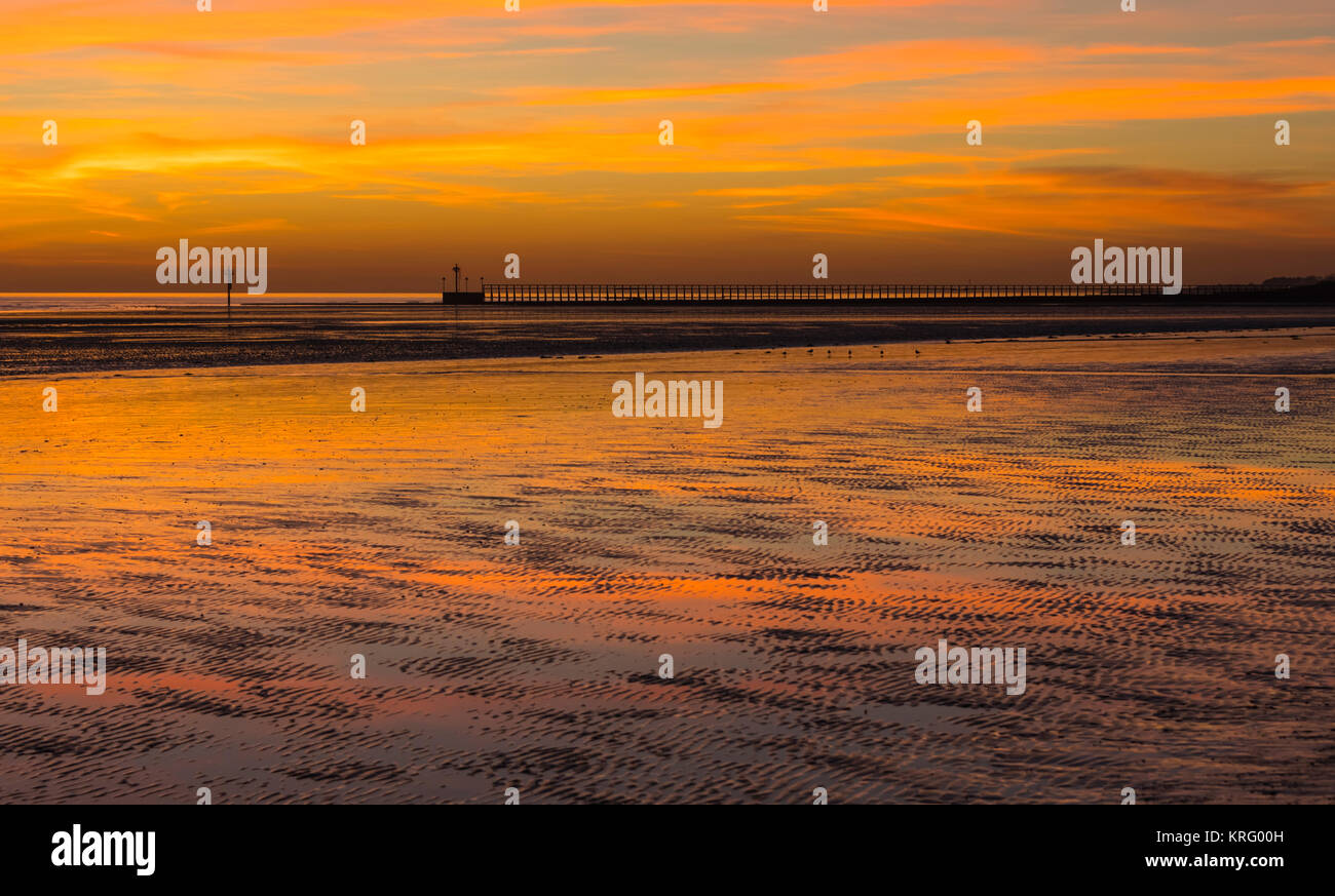 Ciel rouge après le coucher du soleil sur une plage à marée basse en hiver, dans le West Sussex, Angleterre, Royaume-Uni. Banque D'Images
