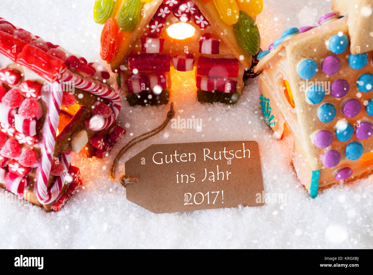 Étiquette avec texte Allemand Guten Rutsch ins Jahr 2017 signifie Bonne année 2017. Maison en pain d'Épices colorés sur la neige et les flocons. Carte de Noël pour le temps des Fêtes Banque D'Images