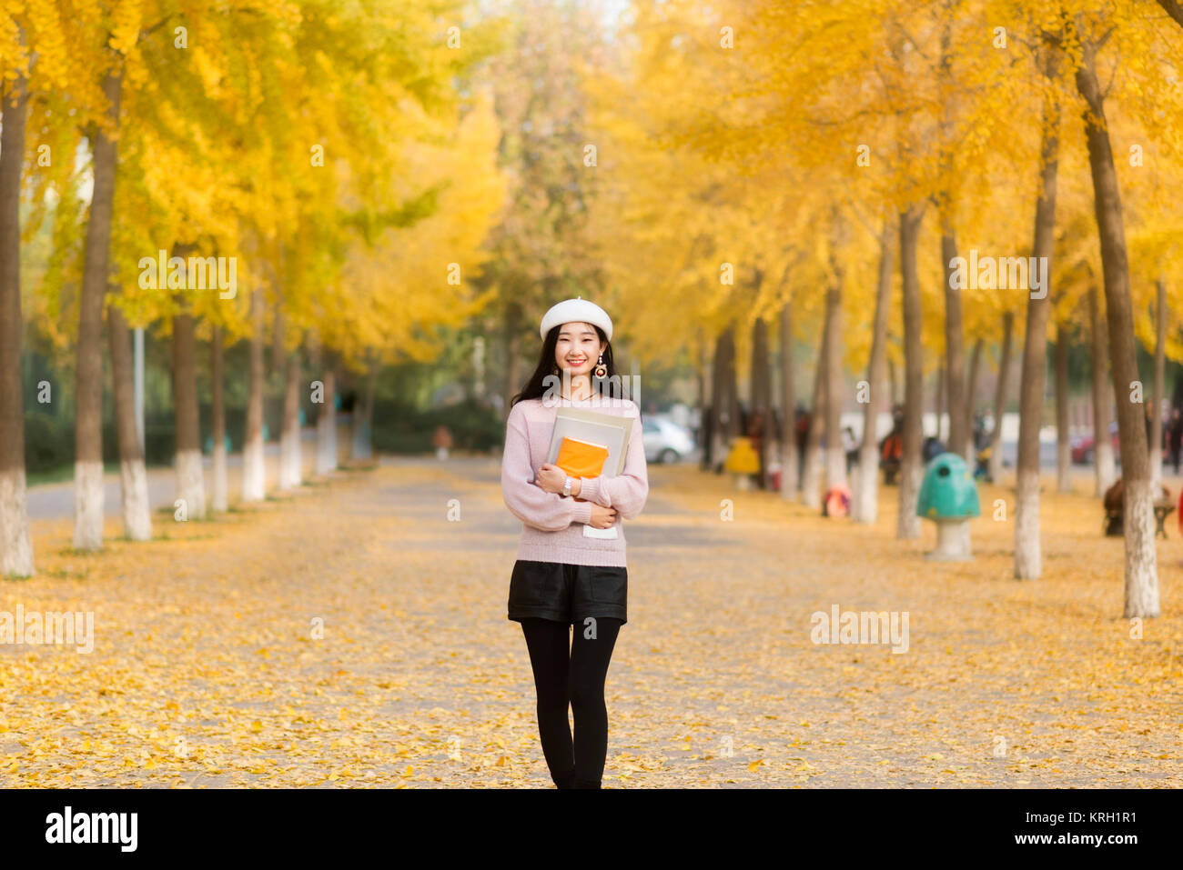 Fille d'automne tenant le livre pour une promenade dans le chemin à travers les bois Banque D'Images