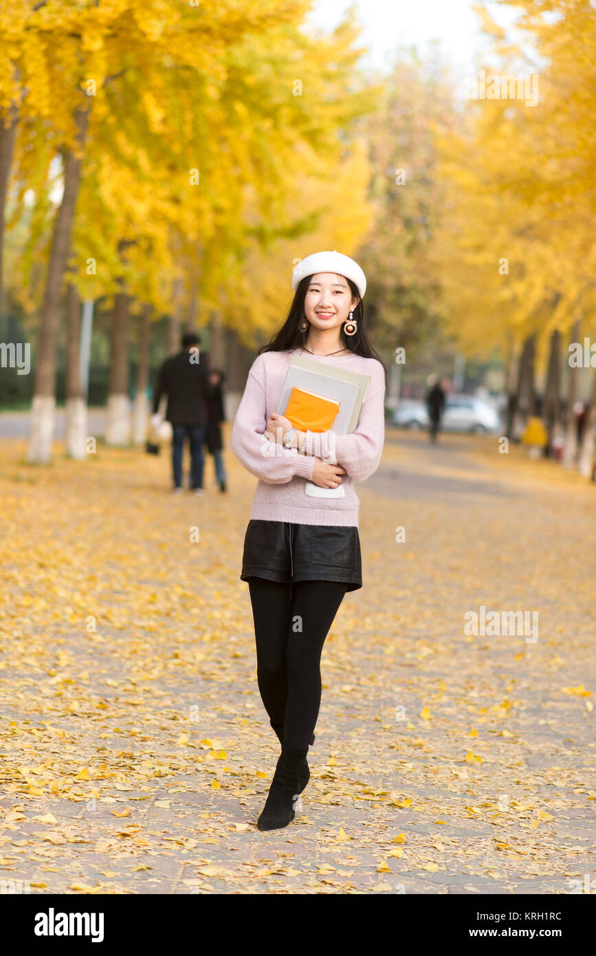 Fille d'automne tenant le livre pour une promenade dans le chemin à travers les bois Banque D'Images